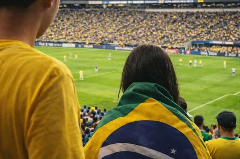 Como funciona a Copa do Mundo sem complicação 2 Torcedores do Brasil observando um jogo em estádio cheio, cena que representa como funciona a copa do mundo e a experiência dos fãs durante o campeonato