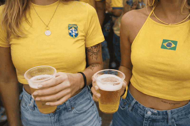 O que é a Copa do Mundo? Entenda o maior torneio de futebol do mundo 2 Torcedoras brasileiras celebrando durante a Copa do Mundo, mostrando na prática o que é a Copa do Mundo e seu impacto cultural